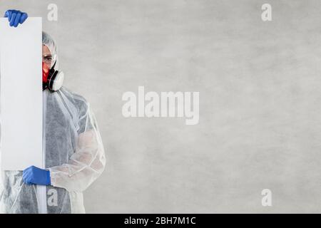 virologo in abbigliamento protettivo tiene spazio pubblicitario nelle sue mani Foto Stock