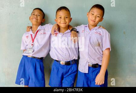 I tre ragazzi studenti thailandesi si abbracciano insieme nella loro divisa sporca dopo aver giocato a calcio. Hua Hin, Thailandia 10 settembre 2016 Foto Stock