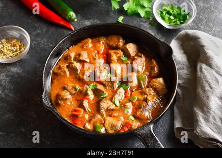 Primo piano di fegatini di pollo peri-peri in padella su fondo di pietra scura. Foto Stock