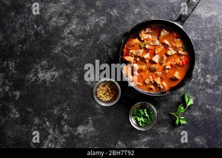 Peri-peri fegatini di pollo in padella su fondo di pietra nera con spazio di testo libero. Vista dall'alto, piatto Foto Stock