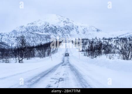 strada ghiacciata e coperta di neve durante una bizzarda nel highland Tundra della Norvegia settentrionale Foto Stock