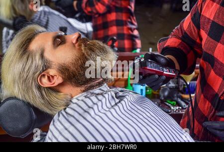 Parrucchiere. Uomo al barbiere. Barbiere e cliente professionale. Barber è una risorsa essenziale per il vostro stile. Rasatura con rasoio. Capelli facciali. Mantenimento della forma della barba. Crescere barba e baffi. Foto Stock