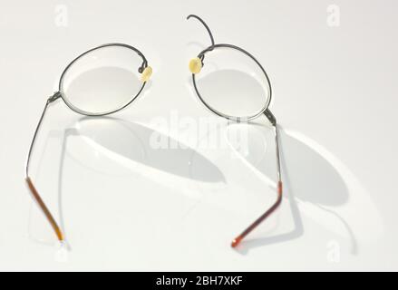 Un paio di occhiali con bordo in filo di titanio che si sono rotti e separati sulla sezione del ponte nasale. Foto Stock