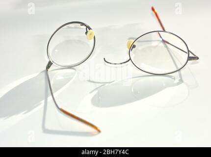 Un paio di occhiali con bordo in filo di titanio che si sono rotti e separati sulla sezione del ponte nasale. Foto Stock