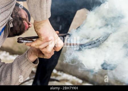 12.01.2019, Oberwiesenthal, Sassonia, Germania - Blacksmith brucia un ferro di cavallo sullo zoccolo di un cavallo. 0MK190112D005CAROEX.JPG [VERSIONE MODELLO: NO, PROPRIETÀ R Foto Stock