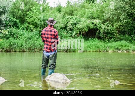 attività di passione. Pesca a mosca riuscita. Fine settimana di estate. pescatore esperto in acqua. fisherman mostra la tecnica di pesca utilizzare canna. Attività sportiva e hobby. Uomo cattura pesce. Uomo maturo pesca a mosca. Foto Stock