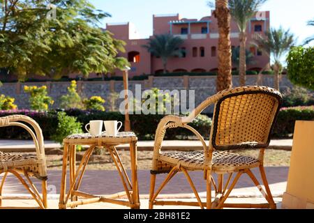 tavolo e sedia in vimini di rattan. Mobili in vimini tavolo in rattan due sedie vicino alla finestra sul balcone. Sedia vuota in camera Foto Stock