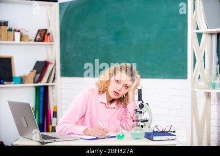 Professione stressante dell'insegnante. Pressione nervosa tesa. Educatore stressante. Ragazza stanca espressione stressante con laptop e microscopio lavoro di indagine biologia e chimica. Scienziato stressante. Foto Stock