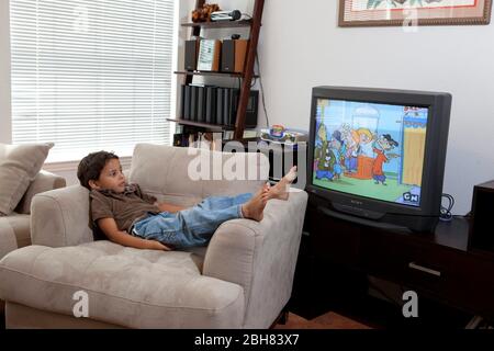 Austin, Texas USA, 22 agosto 2009: Ragazzo messicano-americano di cinque anni che guarda Cartoon Network (CN) a casa mentre ti rilassi su una sedia imbottita. SIG. ©Bob Daemmrich Foto Stock