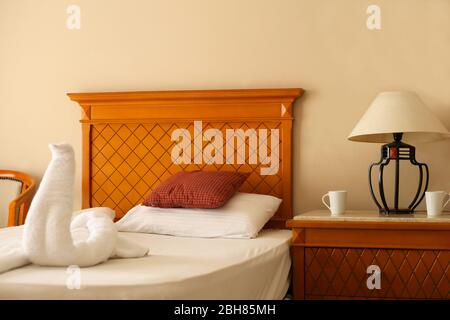 Cuscini sul letto. Camera da letto con arredamento in stile cigno, asciugamani sul letto. Camera d'albergo vuota. Foto Stock