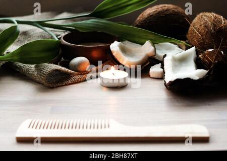 Bagno, concetto spa, sale, cocco, candela di illuminazione, asciugamano di lino, pettinino su sfondo di legno Foto Stock