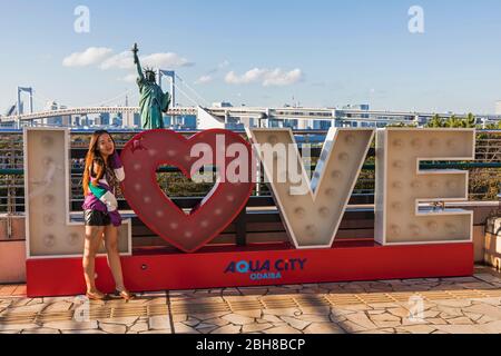 Giappone, Honshu, Tokyo Tokyo città del litorale, Odaiba, ragazza in posa con amore segno Foto Stock