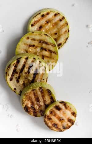 Zucchine grigliate con sale grosso su un piatto bianco. Messa a fuoco selettiva. Foto Stock