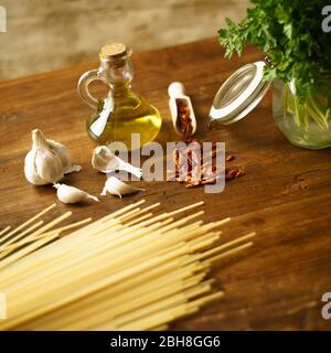 Vista a basso angolo della tipica ricetta italiana spaghetti aglio olio e peperoncino ingredienti con un bicchiere con rametti Foto Stock