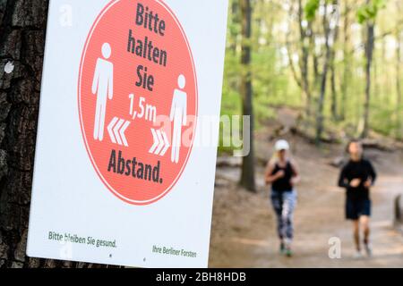 Berlino, Berlino, Germania. 24 Aprile 2020. Due corridori possono essere visti dietro un grande cartello che indica la distanza di sicurezza di 1,5 m a Berlino Schlachtensee, nonostante l'attuale regolamento per contenere la diffusione del coronavirus. Le restrizioni di contatto e una distanza minima di 1.5 metri rimangono in vigore nonostante un parziale rilassamento delle restrizioni alla vita pubblica. Credit: Jan Scheunert/ZUMA Wire/Alamy Live News Foto Stock