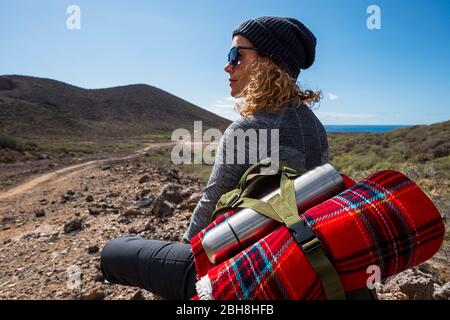 buon viaggiatore con zaino e bottiglia d'acqua seduti a terra in montagna e godendo della vista della valle. Paesaggio rurale, viaggio in Africa, emozione felicità, concetto di vacanza estiva Foto Stock