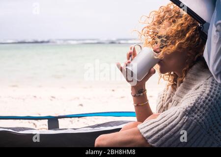 Bella donna di mezza età in campeggio libero all'interno di una tenda sulla spiaggia di sabbia oceano godendo vacanza alternativa - viaggio e avventura concetto di viaggio per la gente di stile di vita moderna caucasica Foto Stock
