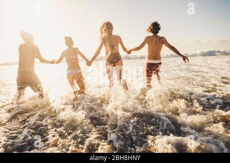 Defocused per il concetto di movimento e attivo le persone hanno divertimento a correre in acqua di mare durante le vacanze estive - amici di gruppo insieme godere della felicità - azione caucasica uomini e donne in amicizia Foto Stock