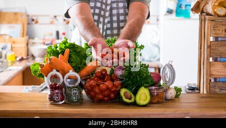 Vegetariano e sano stile di vita alimentare a casa concetto - tavolo in cucina pieno di verdure colorate miste e mani dell'uomo che vi mostra la freschezza - sfondo e energia infredenti per cucinare Foto Stock