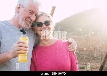 Felice allegro anziano sorriso di coppia e godere insieme per sempre la vita in campagna all'aperto lato con il sole in retroilluminazione dopo una sessione di fitness sana Foto Stock