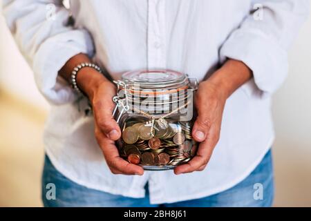 Primo piano di mani donna a casa prendendo un vaso di vetro trasparente pieno di monete e di aereo fuori - economia e soldi per la prossima vacanza di viaggio - familiare concetto di business Foto Stock