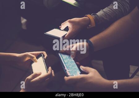 Tre giovani ragazzi caucasici giocano tutti insieme con il telefono cellulare per i videogiochi come clan o team - attività abituale per i millenni a casa persone - tecnologia dipendente concetto persone Foto Stock