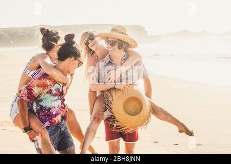 Amici allegri coppia di persone ragazze e ragazzi si divertono insieme al berach in vacanza estiva insieme - uomini che portano le donne e tutti sorridono e ridono molto Foto Stock