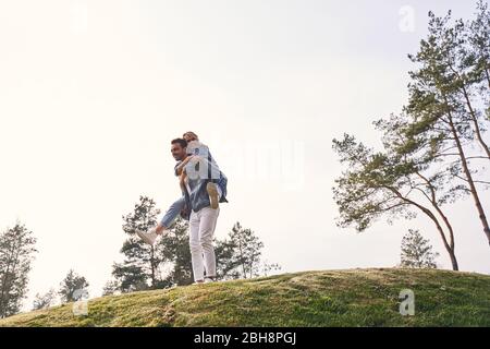 Ragazza felice seduta sul suo ragazzo indietro Foto Stock