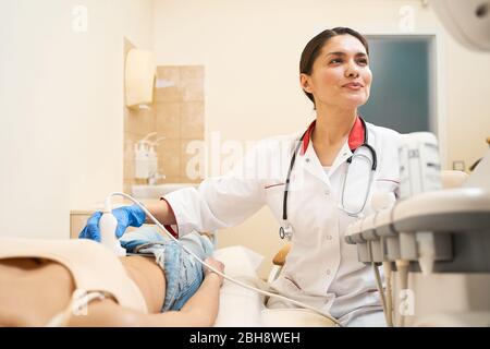 Positivo bruna medico felice facendo ecografo controllo Foto Stock