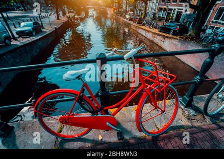 I simboli di Amsterdam: Rosso bicicletta parcheggiata su un ponte, Paesi Bassi. Viaggi, romanticismo, vacanza. Il concetto di cultura Foto Stock