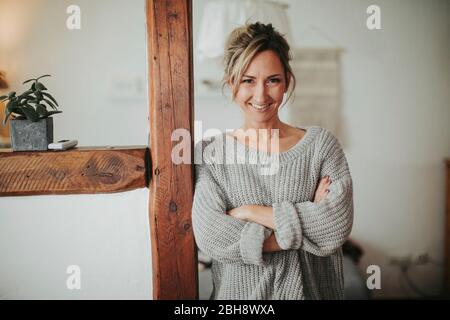 junge Frau in ihrer Wohnung, Arme verschränkt, lächeln, Halbporträt Foto Stock