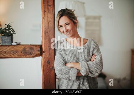 junge Frau in ihrer Wohnung, Arme verschränkt, lächeln, Halbporträt Foto Stock