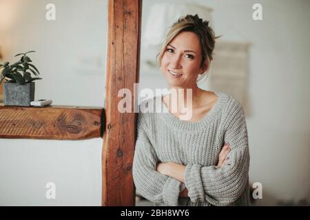 junge Frau in ihrer Wohnung, Arme verschränkt, lächeln, Halbporträt Foto Stock