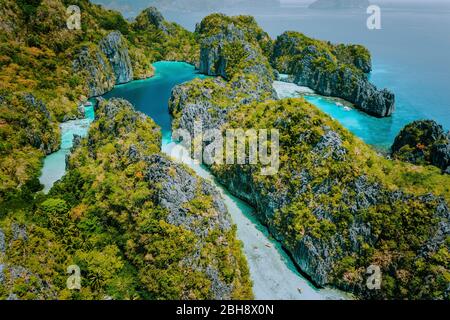 Vista aerea dei droni bella laguna tropicale bassa Grande e piccola esplorata all'interno da turisti su kayak circondato da frastagliate scogliere carsiche calcaree. El Nido, Palawan Filippine. Foto Stock