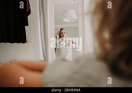 Donna si alza davanti allo specchio, abiti Foto Stock