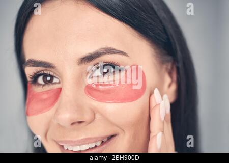 Ragazza caucasica allegra con tamponi di gel di collagene Foto Stock