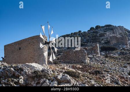 Mulini a vento in pietra, situati su una collina a Pinakaino, Plateau Lasithi. Cielo blu brillante. Creta, Grecia. Foto Stock