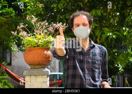 Giovane con maschera di prevenzione facendo il segno 'ok' Foto Stock