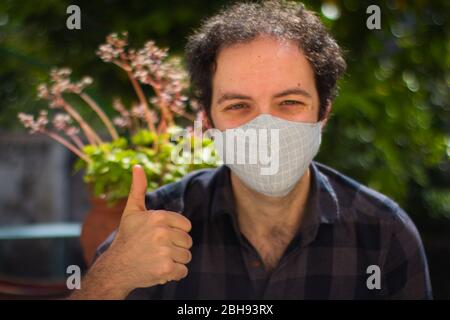 Giovane con maschera di prevenzione facendo il segno 'ok' Foto Stock