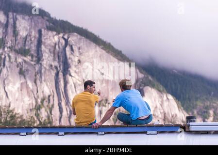 Uomo che indica roccia arrampicata roccia con il dito sulla cima della scuola bus Foto Stock