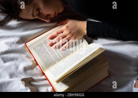Donna che dorme accanto ad un libro aperto. Foto Stock