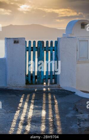 I raggi di luce cadono attraverso la griglia blu della porta. Nuvole e il mare di Santorini, Thira, Cicladi, Grecia, Egeo meridionale, Grecia Foto Stock