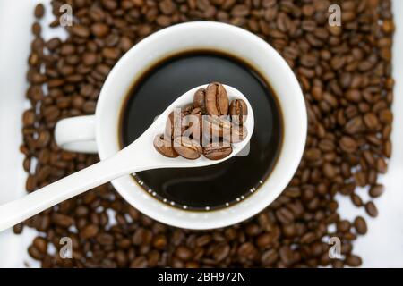 tazza da caffè bianca, cucchiaio e chicchi di caffè tostati isolati su sfondo bianco. vista dall'alto. Foto Stock