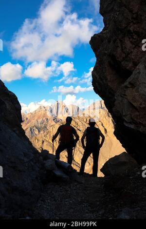 Due escursionisti che guardano il gruppo del Gran Vernel in una piccola forcella lungo l'Alto sentiero Bepi Zac, il crinale Costabella, il gruppo Marmolada, le Dolomiti, la Val di Fassa, la provincia di Trento, il Trentino-Alto Adige, Italia Foto Stock