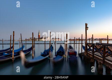 Gondole a Venezia al tramonto in Piazza San Marco in lunga esposizione, San Giorgio maggiore sullo sfondo Foto Stock