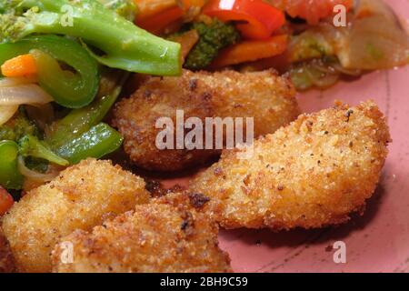 Pepite di pollo fritte e insalata sul piatto. Foto Stock
