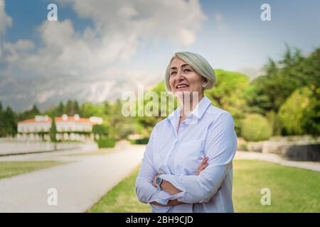 Ritratto donna matura mentre riposa al parco Foto Stock