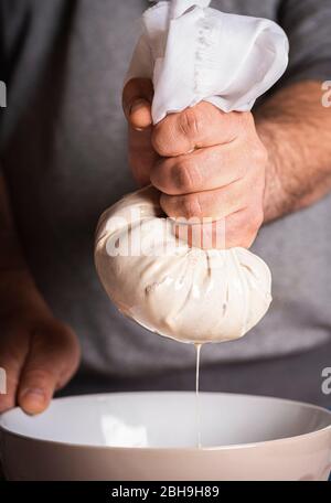 Uomo che fa l'orchata, spremendo le mandorle e la pasta di riso. L'horchata è una bevanda tradizionale messicana a base di riso e mandorle imbevute di latte, aromatizzata wi Foto Stock