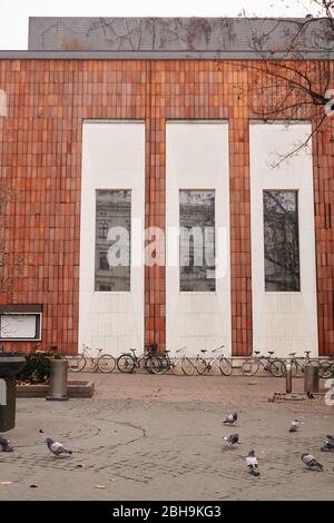 Tipica casa moderna con pareti rosse e bianche e grandi finestre con grande quantità di biciclette parcheggiate davanti ad essa. Marciapiede e piccioni di fronte al pict Foto Stock