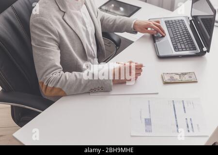 Un contabile maschile lavora in un pc in un ufficio a casa. Libro paga e prelievo di contanti Foto Stock